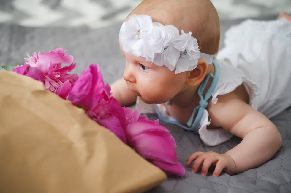 Cute newborn baby smelling flowers